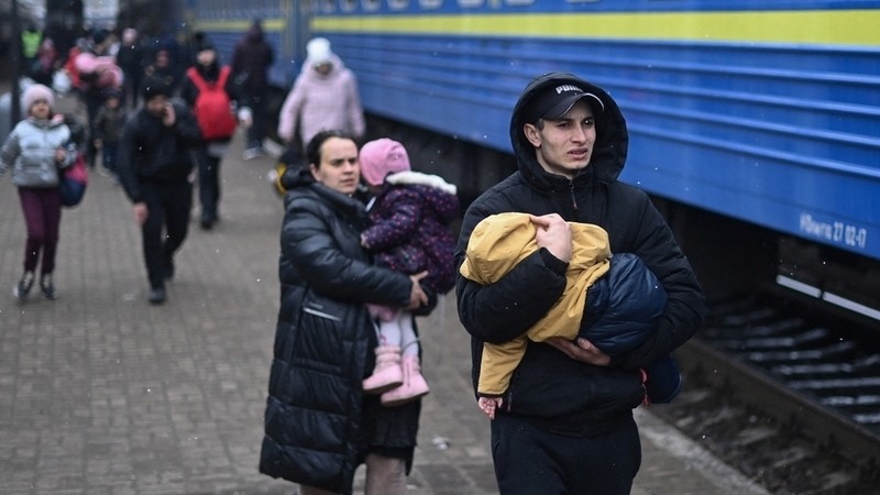 A man carries a baby as they rush to board a train taking refugees to Poland at Lviv train station, western Ukraine, on March 5, 2022. &#8211; The UN Human Rights Council on March 4, 2022, overwhelmingly voted to create a top-level investigation into v